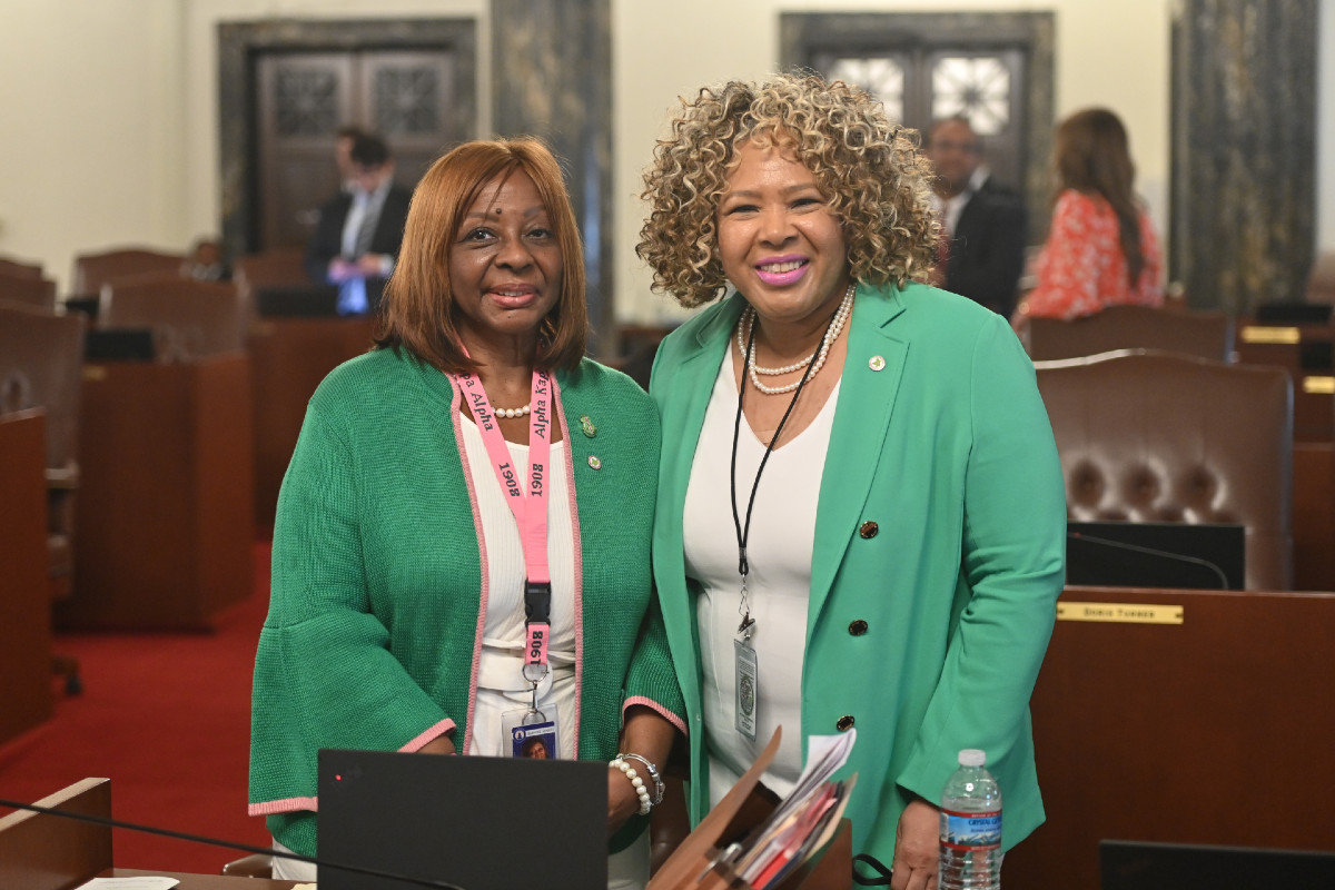 Senator Hunter smiles while standing next to an Alpha Kappa Alpha representative on the Senate floor.